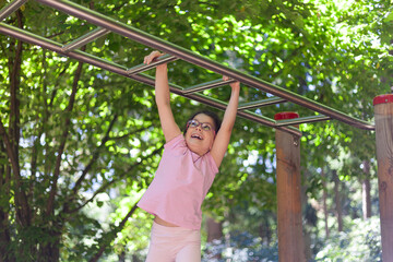 Little girl having fun on the playground at the day time. Concept of healthy lifestyle.
