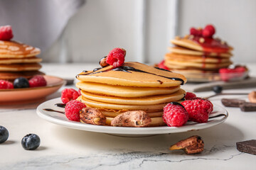Plate of tasty pancakes with raspberries and nuts on table