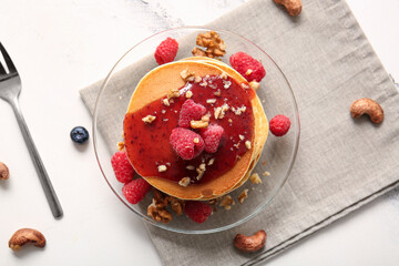 Plate of tasty pancakes with raspberries and nuts on white marble background
