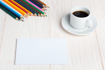 Cup of coffee, a Notepad, coloured pencils on the table