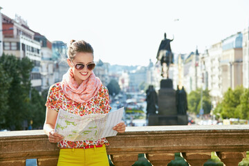 Catch the spirit of old Europe in Prague. Smiling young woman in sunglasses looking at the map near National Museum at Wenceslas Square