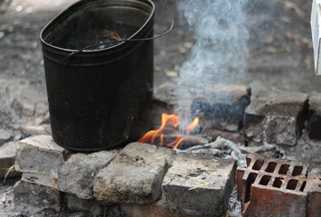 Tea is brewed in a pot on a fire in the forest. Bonfire. camping pot. Cooking food and drinks on a...