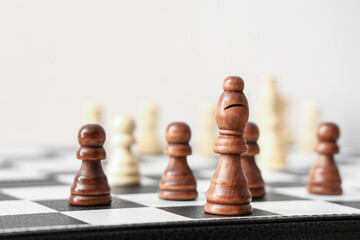 Chess pieces on game board near light wall, closeup