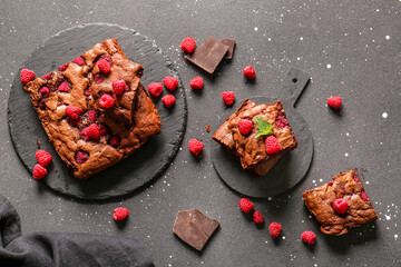Boards with raspberry chocolate brownie and pieces on black background