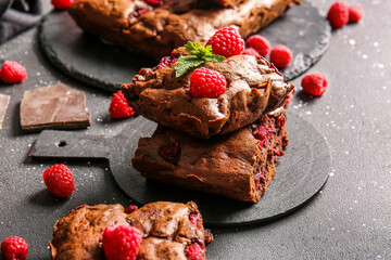Board with pieces of raspberry chocolate brownie on black table