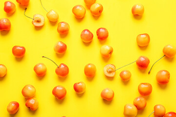 Many sweet yellow cherries on yellow background