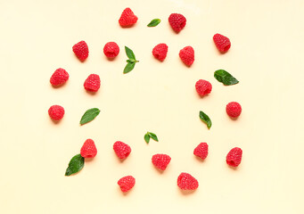 Frame made of fresh raspberries and mint on yellow background