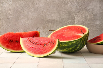 Half of fresh watermelon with pieces on white tile table