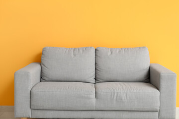 Cozy grey sofa near orange wall