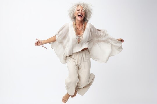Full length portrait of a happy senior woman jumping isolated on a white background