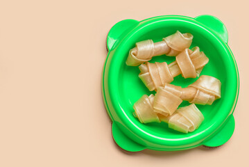 Bowl of dog treats on color background