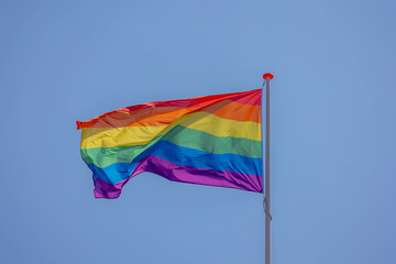 Celebration of pride month, Colourful rainbow flag hanging waving in the air with blue sky as background, Symbol of Gay, Lesbian, Bisexual and Transgender, LGBTQ community, Worldwide social movements.