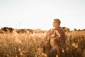 Young man enjoying tranquil morning in wheat field having a peaceful quiet moment in nature 