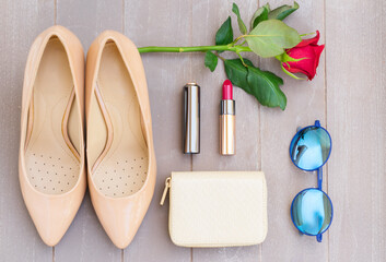 Nude colored high heels still life with wallet, rose flower, sun glasses and red lipstick