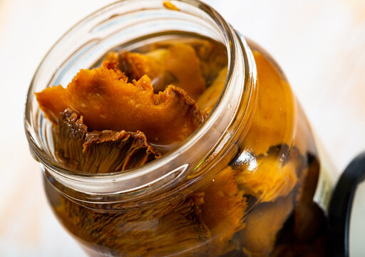 Closeup of chopped marinated forest mushrooms lactarius deliciosus in glass jar. Homemade pickles