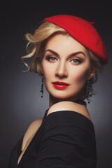 Beautiful lady in red beret. Beauty portrait. Red lips. Over black background.