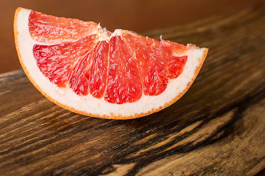 Slice of red juicy grapefruit on vintage wooden board