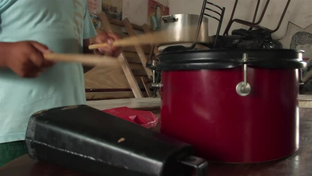Hands of a Young Boy Playing Drum and Cowbell at his Home in Argentina. Close Up.  