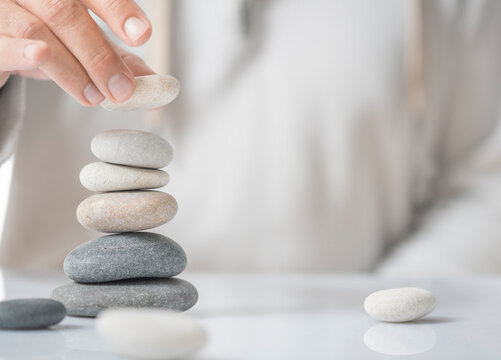 Horizontal image of a man stacking pebbles on a table with copyspace for text. Concept of personal development or self realization.