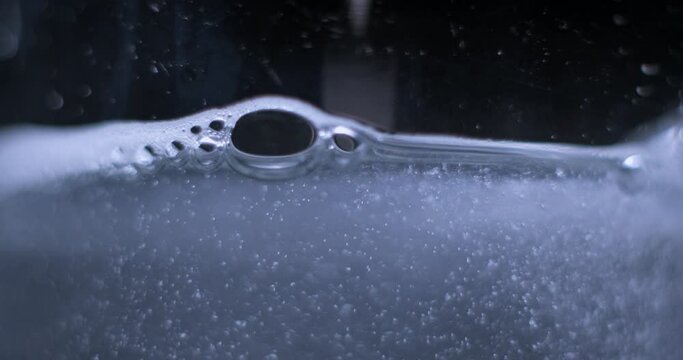 Aspirin falling into a glass of water on black background, slow motion 4K Pro Res