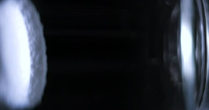 Aspirin falling into a glass of water on black background, vertical slow motion 4K Pro Res