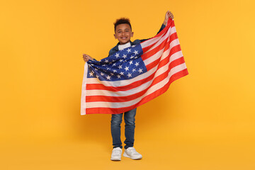 4th of July - Independence Day of USA. Happy boy with American flag on yellow background
