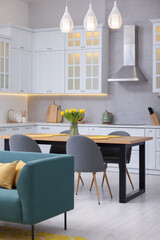 Spring atmosphere. Stylish kitchen interior with comfortable furniture and bouquet of beautiful yellow tulips