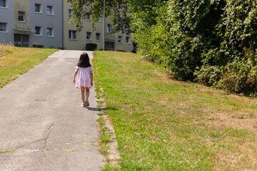 Fototapeta na wymiar Little girl walking on the path in the park. Back view.