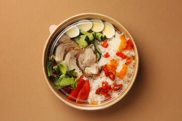 Tasty food in container on beige background, top view