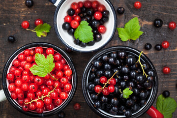 Fresh delicious organic red and black currants in a mugs on wooden table