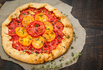 Delicious homemade rustic open pie (galette) with tomato, thyme and goat cheese