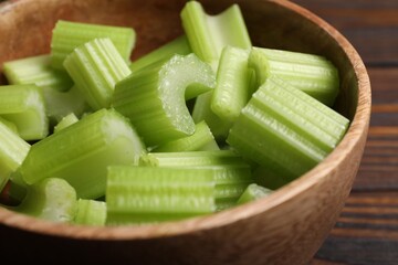 Fresh cut celery stalks in bowl on wooden table, closeup