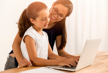 Mother helping her little daughter how to use a computer