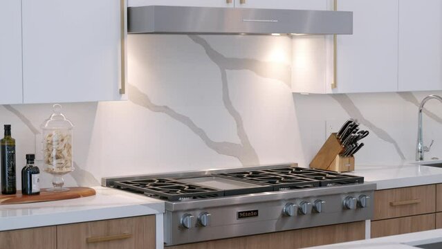 Up-to-date gas stove and household hood from stainless steel being built into modern furniture. Interior of modern kitchen with appliances