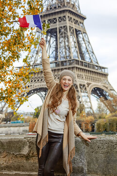 Autumn getaways in Paris. smiling young tourist woman on embankment in Paris, France rising flag