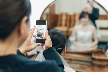 ブライズルーム・控え室で花嫁・新婦の写真をスマホで撮るプランナーの女性
