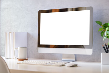 Computer monitor and office supplies on white table in modern workplace.