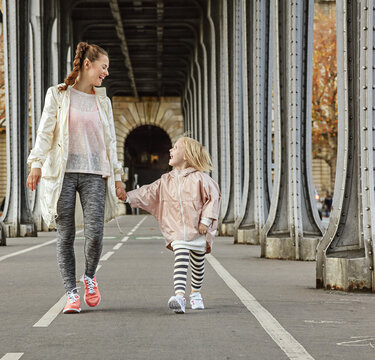 Year round fit & hip in Paris. Full length portrait of smiling healthy mother and child in sport style clothes on Pont de Bir-Hakeim bridge in Paris walking