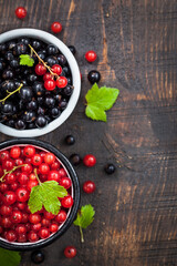 Fresh delicious organic red and black currants in a mugs on wooden table