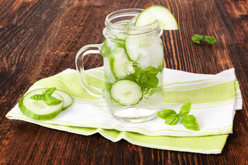 Cucumber and basil lemonade on brown wooden rustic vintage table. Healthy summer drink.