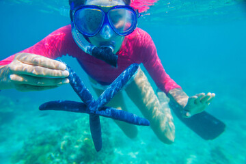 Underwater photo of happy girl with a giant starfish