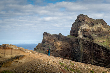 Fototapeta premium Tourist is watching his gps map near the high cliff. Scenic hiking path to the eastern cape of Madeira island. Madeira, Portugal.