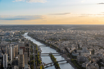 The Seine River flows through the heart of Paris, France, as seen from atop the Eiffel Tower during sunset. - obrazy, fototapety, plakaty