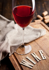 Glass of red wine on wooden board with kitchen towel and with letters and corks. Great for bar and restaurant. Still Life Photography