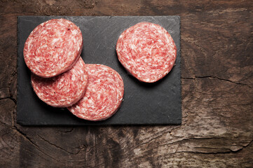 Slices of fresh salami on board ready for cooking.