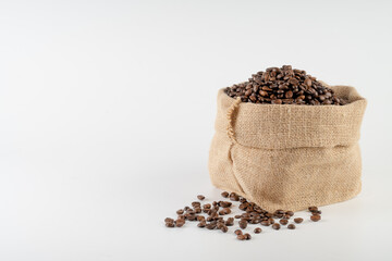 Fototapeta na wymiar Roasted coffee beans falling in a burlap sack. Sackcloth bag with coffee beans, isolated on white background. Coffee export.