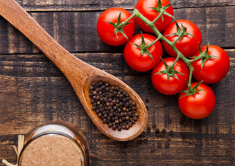 Fresh tomatoes with basil and spoon with pepper on grunge wooden board. Jar with spices