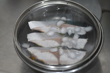 下茹でしたブリを氷水で冷やす様子