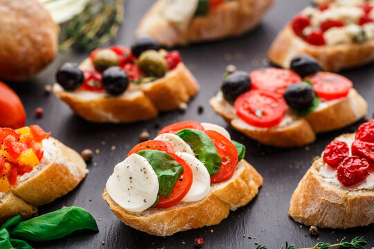 Italian bruschetta with tomatoes, mozzarella cheese and herbs on a slate background