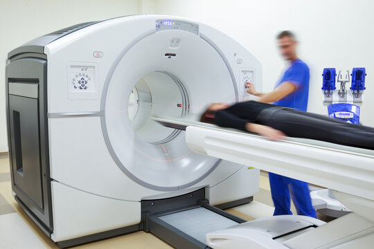 Blurred Doctor Figure Operating A Pet Scanner With Patient On In A Modern Hospital Oncology